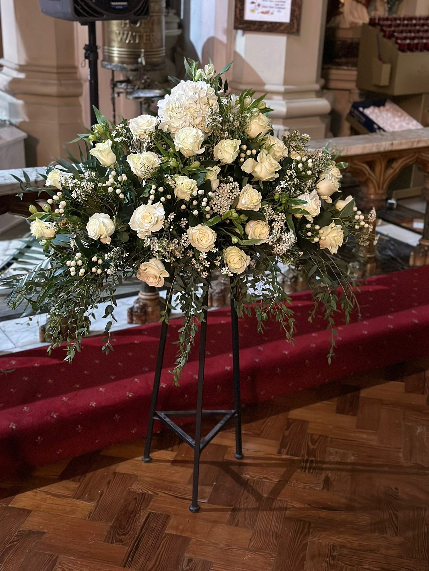 White roses funeral spray on tripod stand