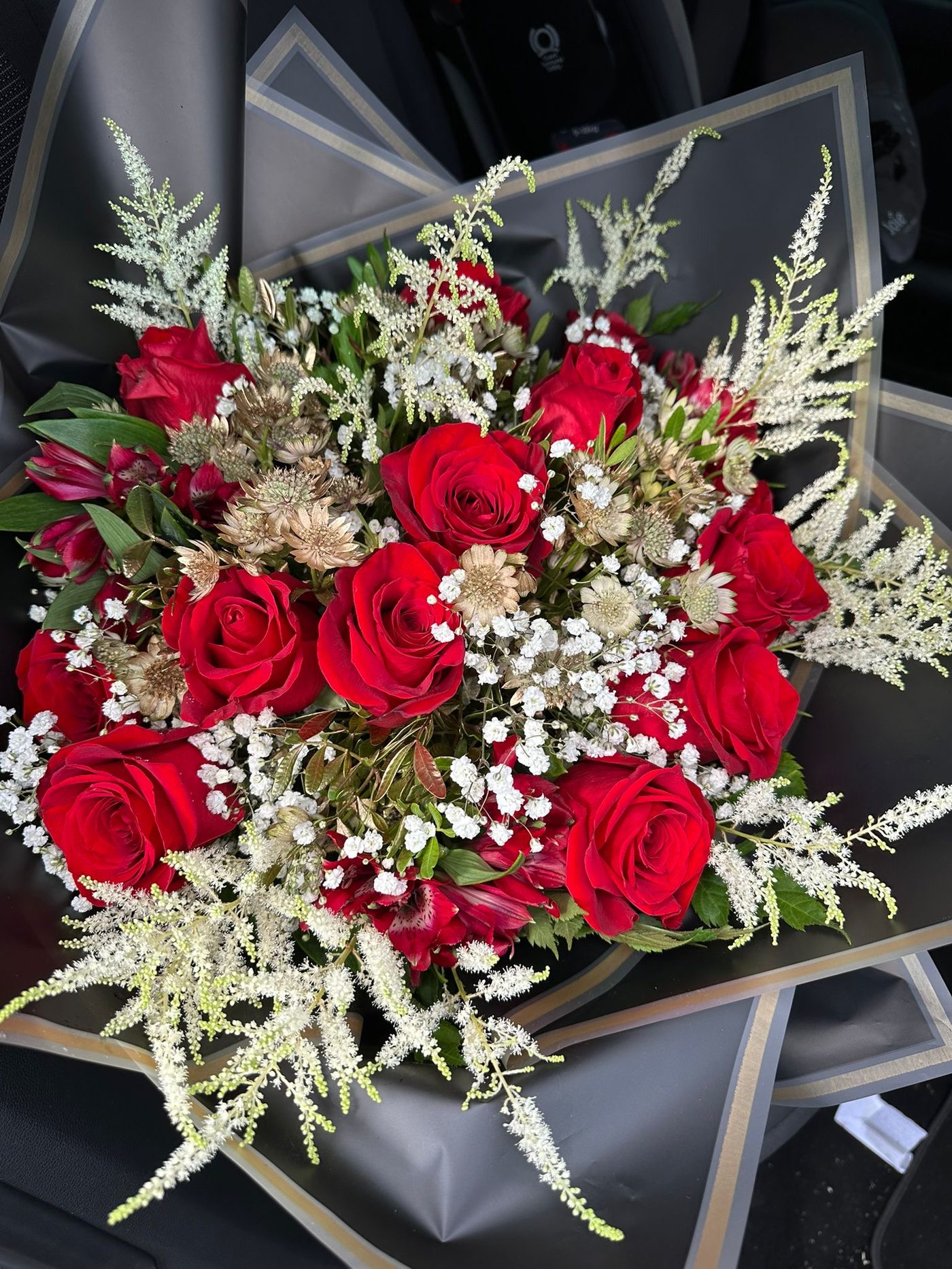 Red roses with dried gold accents in black wrap
