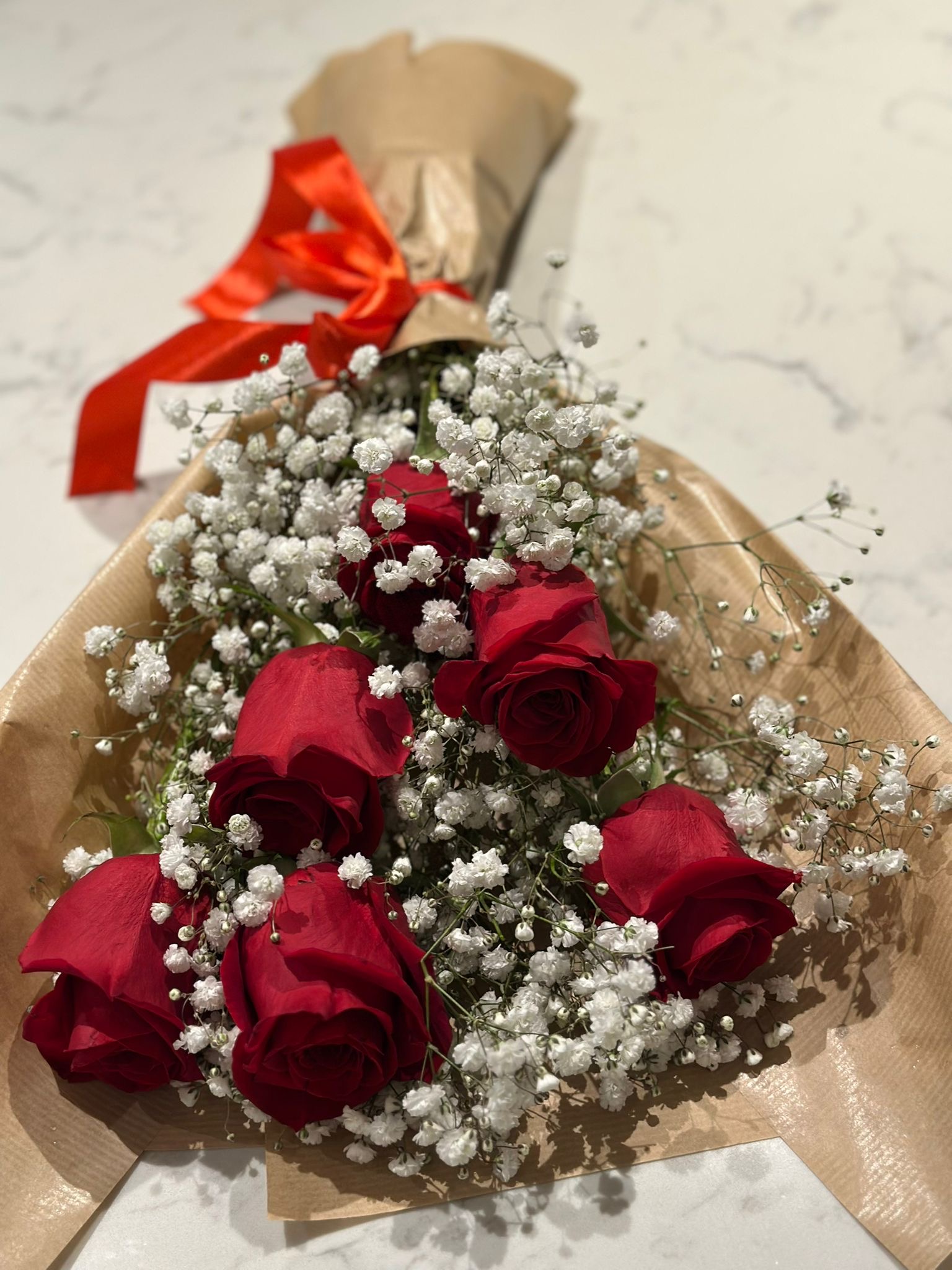 Red roses with babys breath in kraft paper